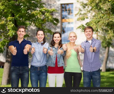 education and people concept - group of smiling students standing and showing thumbs up