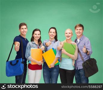 education and people concept - group of smiling students standing and showing thumbs up