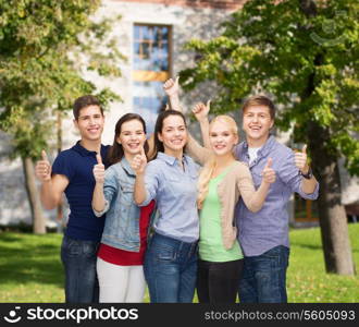 education and people concept - group of smiling students standing and showing thumbs up