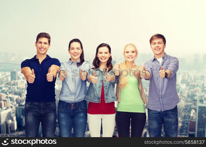 education and people concept - group of smiling students standing and showing thumbs up