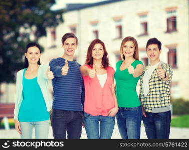 education and people concept - group of smiling students standing and showing thumbs up