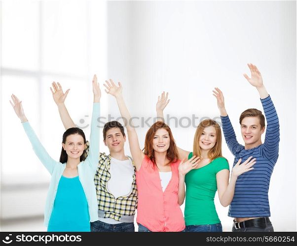 education and people concept - group of smiling students standing and waving hands