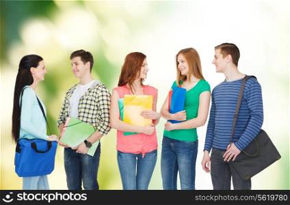 education and people concept - group of smiling students with bags and folders having discussion