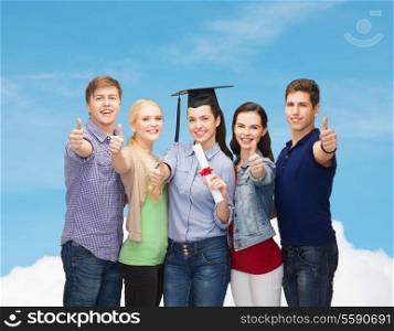 education and people concept - group of standing smiling students with diploma and corner-cap showing thumbs up