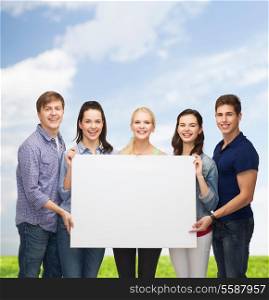 education and people concept - group of standing smiling students with white blank board