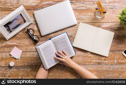 education and people concept - hands of woman reading book at wooden table. hands of woman reading book at wooden table
