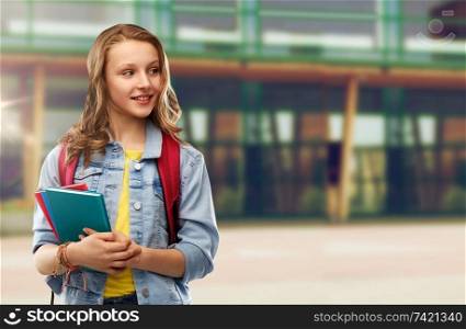 education and people concept - happy smiling teenage student girl with bag and books over school yard background. happy smiling teenage student girl with school bag