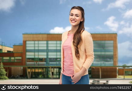 education and people concept - happy smiling young student woman in cardigan over school background. smiling young student woman over school background