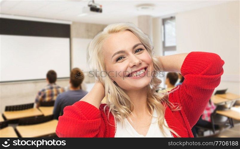 education and people concept - happy smiling young woman over classroom at high school on background. happy smiling young woman over school classroom