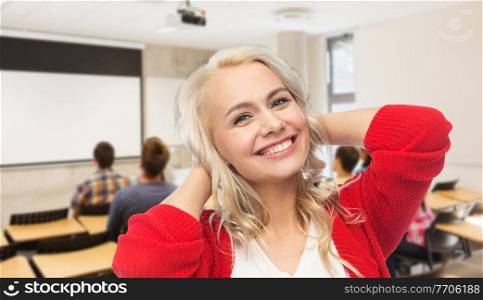 education and people concept - happy smiling young woman over classroom at high school on background. happy smiling young woman over school classroom