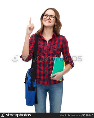 education and people concept - smiling female student in eyeglasses with bag and notebooks showing direction