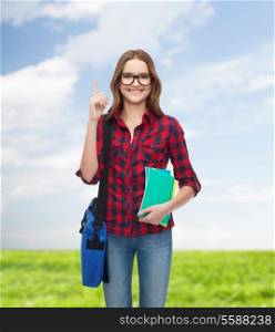 education and people concept - smiling female student in eyeglasses with bag and notebooks showing direction