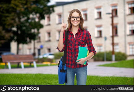 education and people concept - smiling female student in eyeglasses with bag and notebooks showing direction