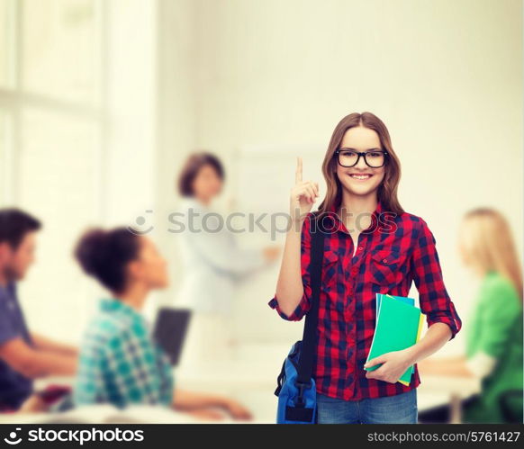 education and people concept - smiling female student in eyeglasses with bag and notebooks showing direction