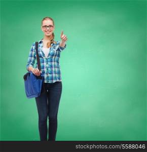 education and people concept - smiling female student in eyeglasses with laptop bag showing thumbs up on green board background