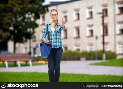 education and people concept - smiling female student in eyeglasses with laptop bag showing thumbs up