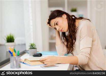 education and people concept - tired female student with book learning at home. tired female student with book learning at home