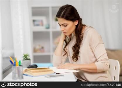 education and people concept - tired female student with book learning at home. tired female student with book learning at home. tired female student with book learning at home