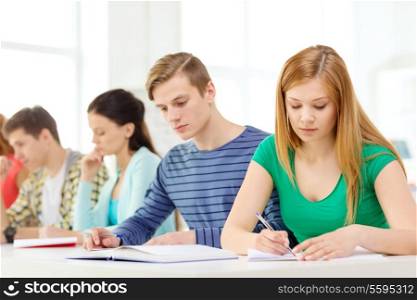 education and school concept - five tired students with textbooks and books at school