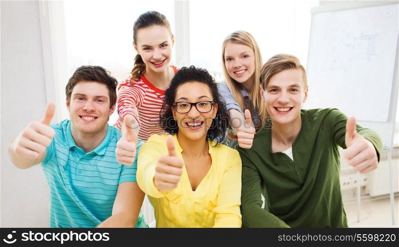 education and school concept - group of smiling students at school showing thumbs up