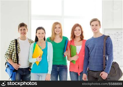 education and school concept - group of smiling students with bags and folders at school