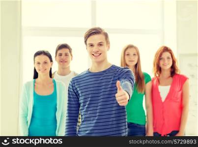 education and school concept - group of smiling students with teenage boy in front showing thumbs up