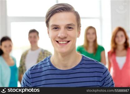 education and school concept - group of smiling students with teenage boy in front