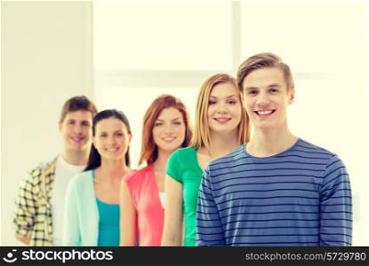 education and school concept - group of smiling students with teenage boy in front