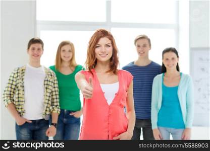 education and school concept - group of smiling students with teenage girl in front showing thumbs up