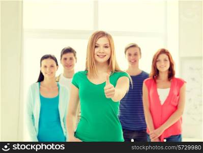 education and school concept - group of smiling students with teenage girl in front showing thumbs up