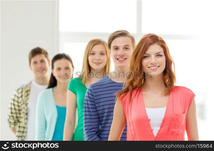 education and school concept - group of smiling students with teenage girl in front