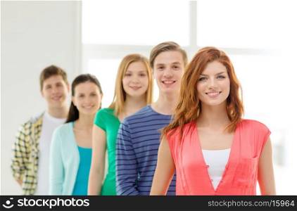 education and school concept - group of smiling students with teenage girl in front