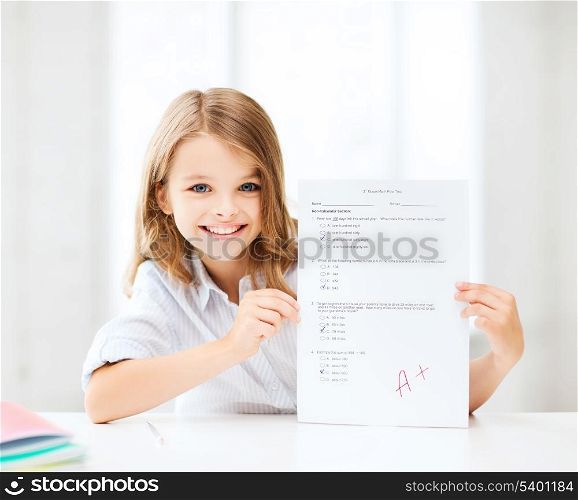 education and school concept - little school girl with test and A grade at school