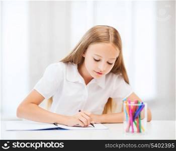 education and school concept - little student girl drawing at school