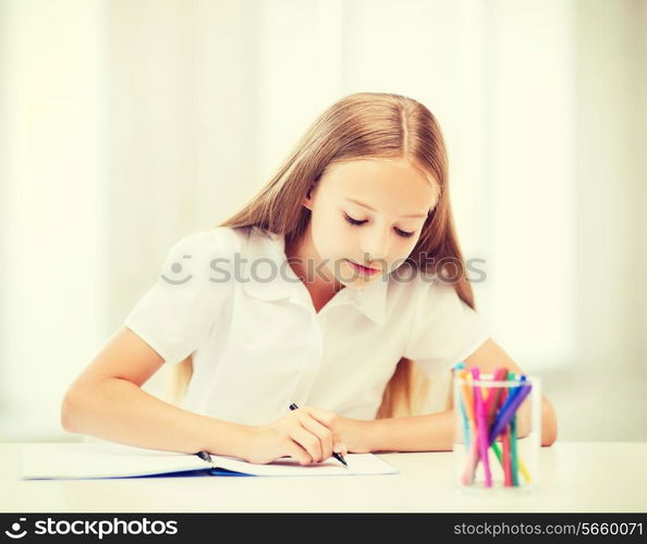 education and school concept - little student girl drawing at school