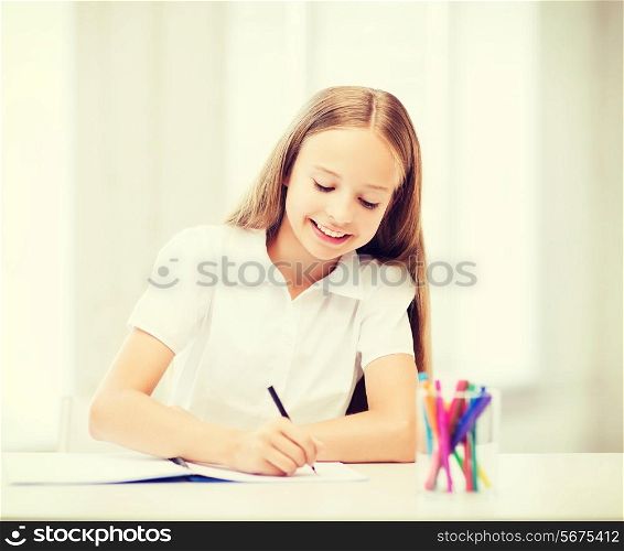 education and school concept - little student girl drawing at school