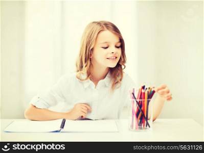 education and school concept - little student girl drawing with pencils at school