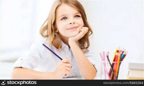 education and school concept - little student girl drawing with pencils at school. girl drawing with pencils at school