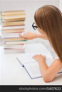 education and school concept - little student girl in black eyeglasses with many books at school