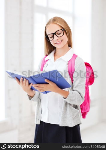 education and school concept - little student girl reading book at school