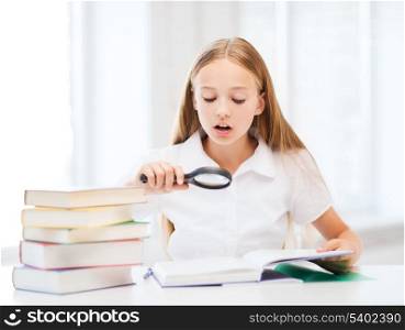 education and school concept - little student girl reading book with magnifier at school