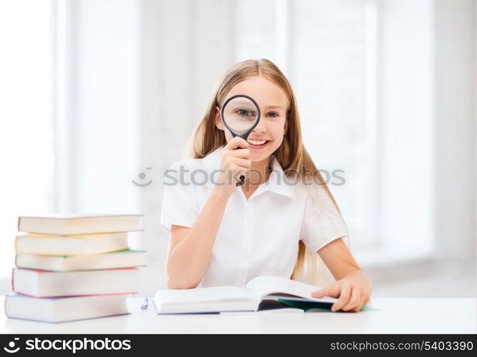 education and school concept - little student girl reading book with magnifier at school