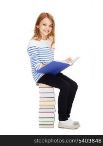 education and school concept - little student girl sitting on stack of books