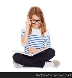 education and school concept - little student girl studying and reading book