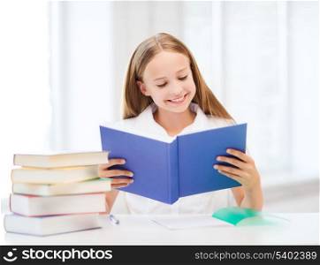 education and school concept - little student girl studying and reading book at school
