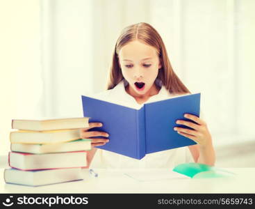 education and school concept - little student girl studying and reading book at school