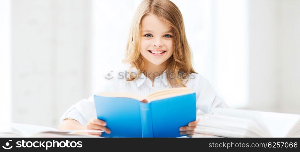 education and school concept - little student girl studying and reading book at school. student girl studying at school