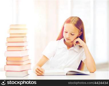 education and school concept - little student girl studying and reading books at school. student girl studying at school