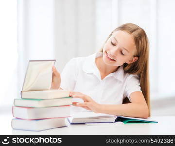 education and school concept - little student girl studying and reading books at school