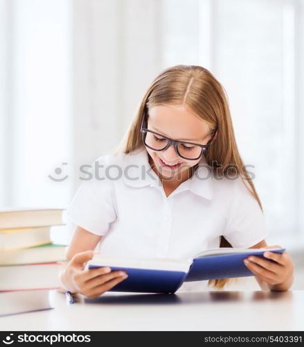 education and school concept - little student girl studying and reading books at school